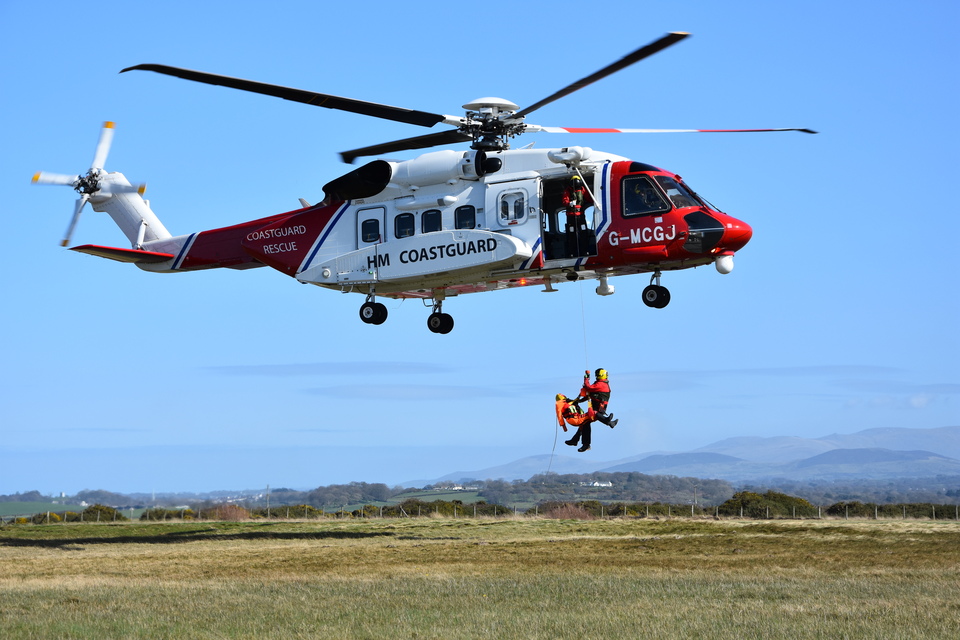 A hovering HM Coastguard search and rescue helicopter