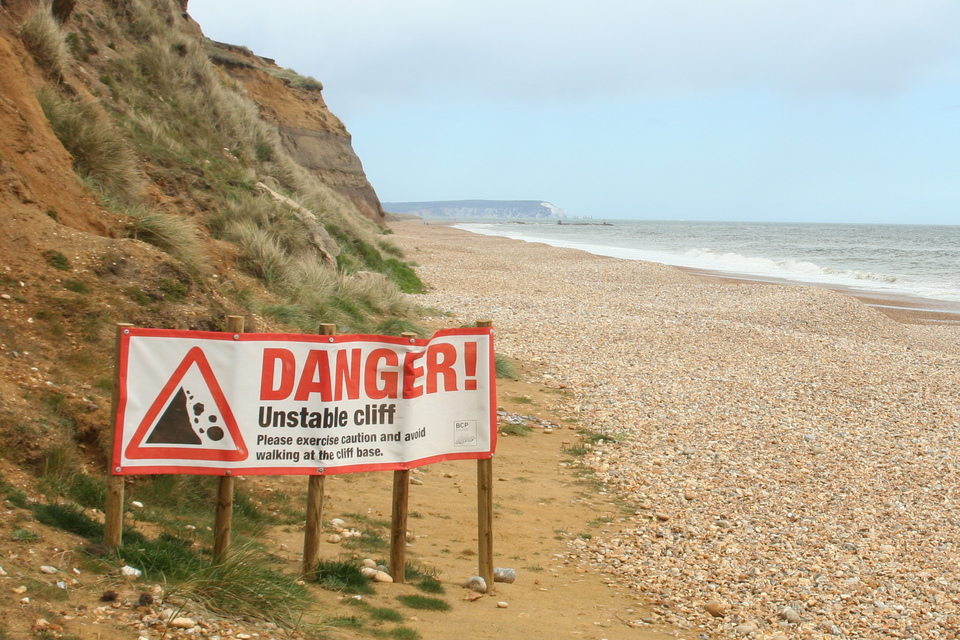 A warning sign at the base of a cliff