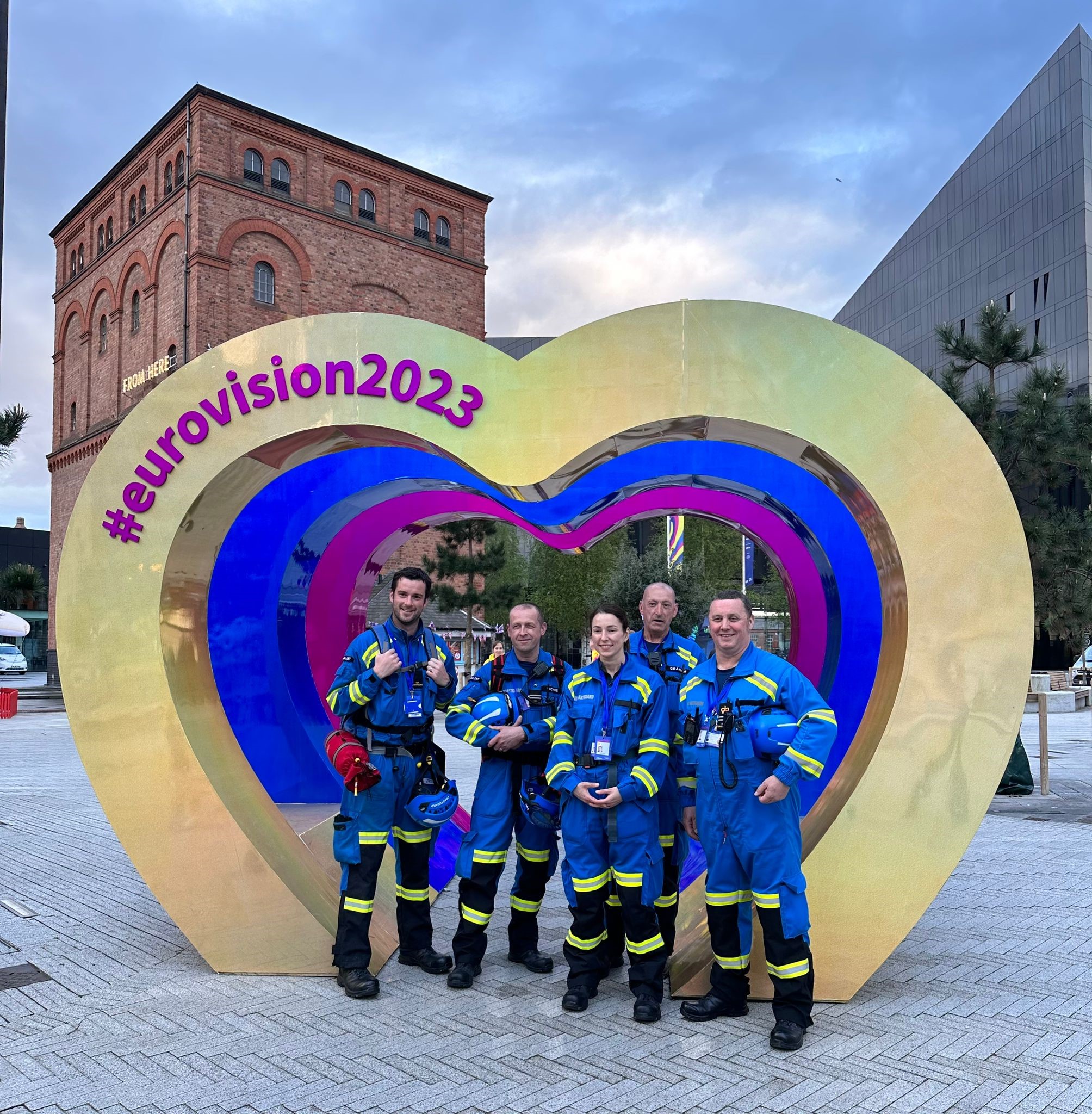 Five coastguards in uniform in front of Eurovision heart photo space in Liverpool