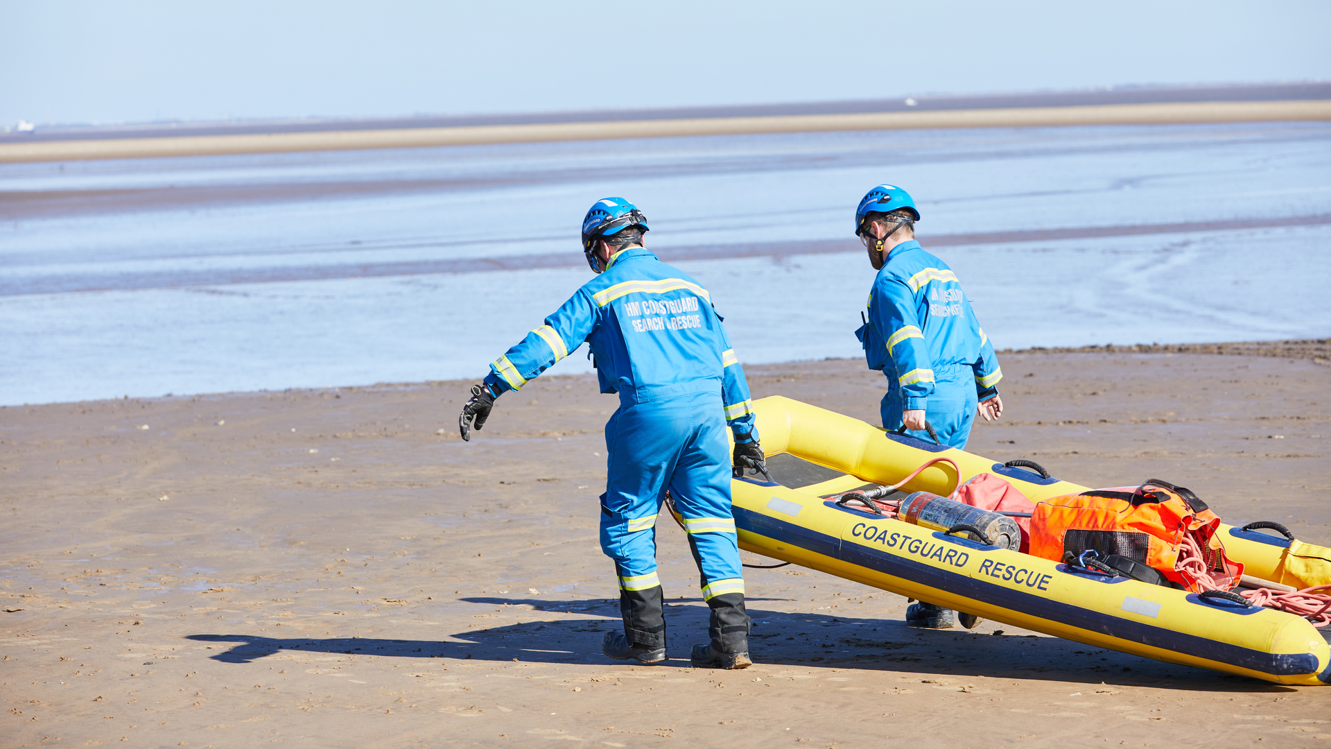 Two Coastguard Rescue Officers pulling a mud rescue sledge