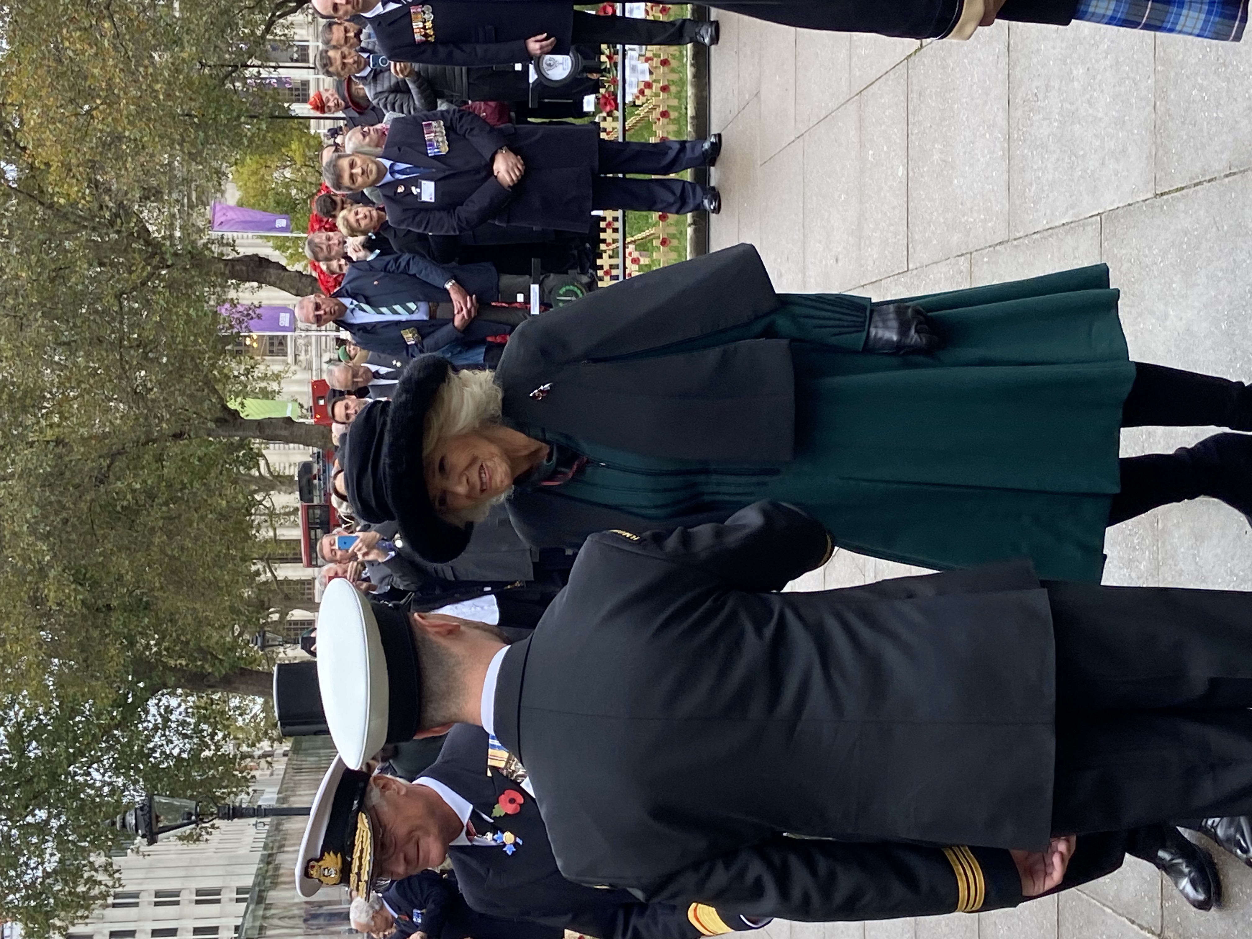 Queen Camilla smiles as she approaches a uniformed HM Coastguard officer with back to camera