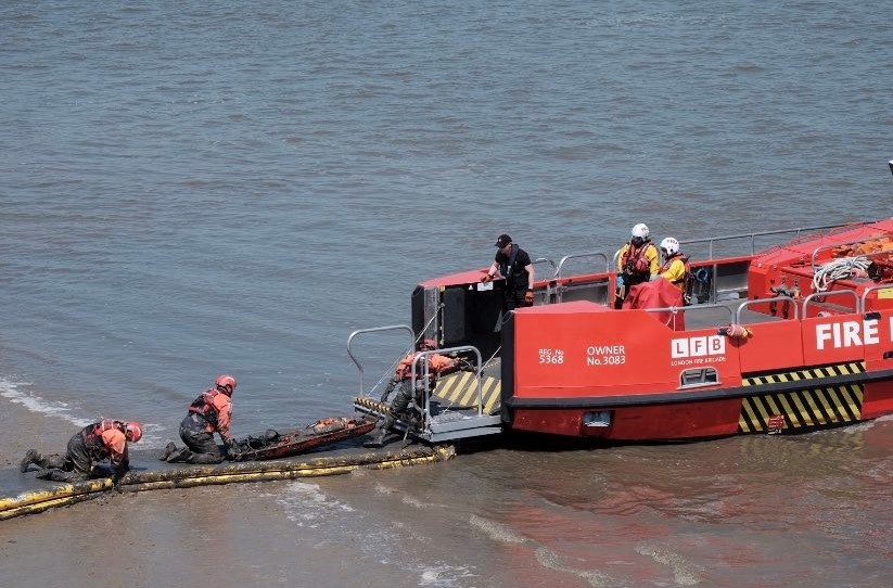 A fire and rescue boat beside mud on the River Thames
