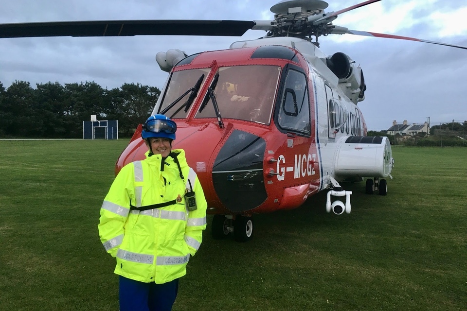 Sarah Stanton-Nadin in front of a coastguard rescue helicopter.