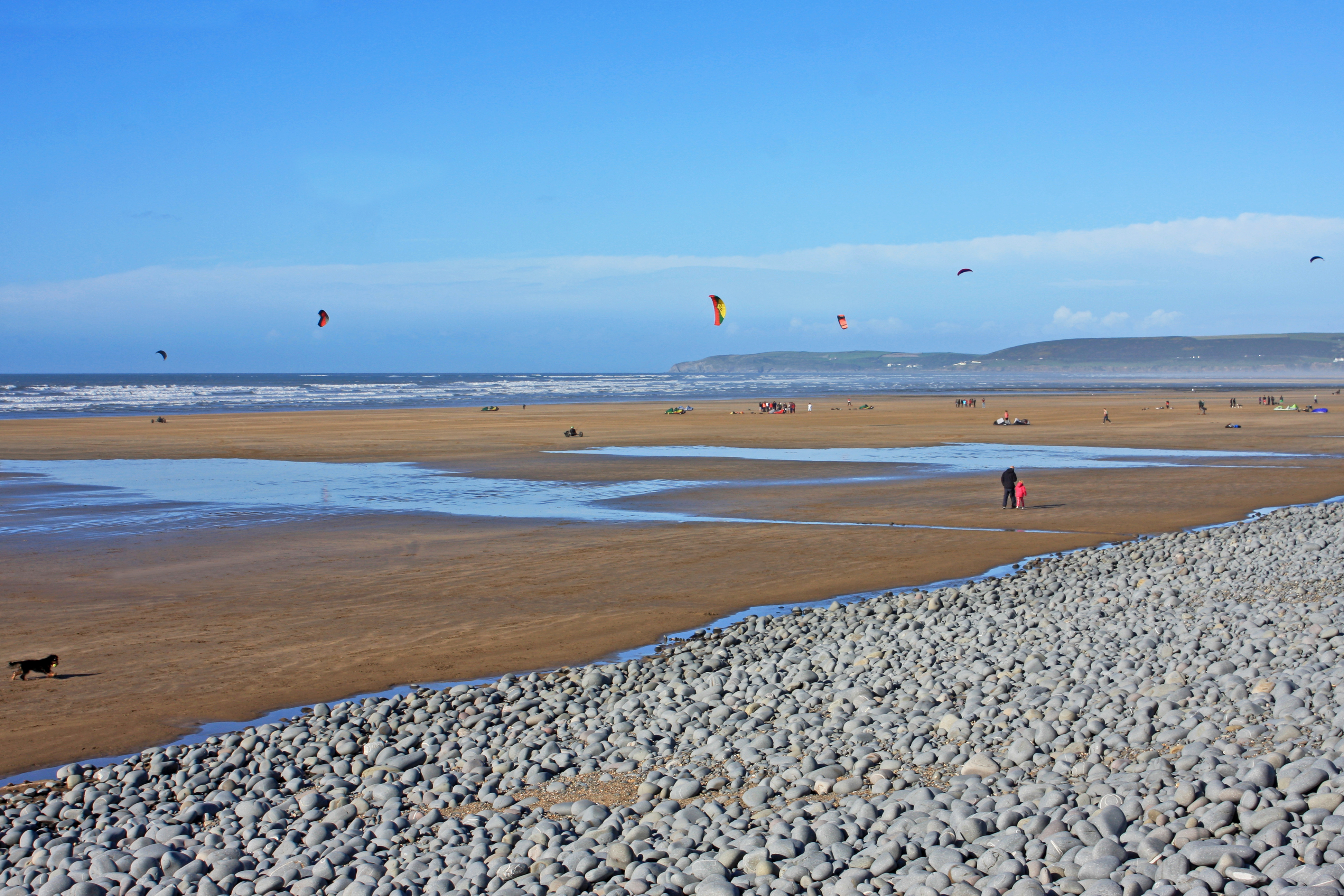 Landscape wide-angle of Westward Ho! beach with people and kitesurfers visible