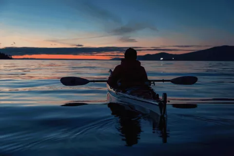 A canoeist out at sea at night.