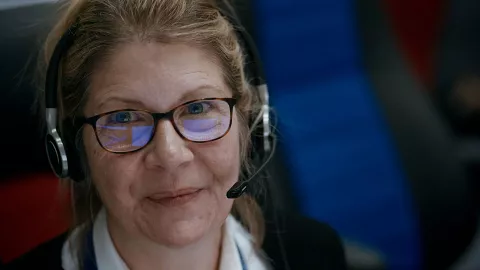 Maritime Operations Officer Rachel with headphones and glasses smiling at the camera from the documentary