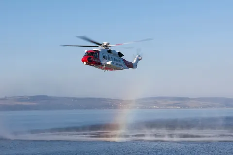 An HM Coastguard search and rescue helicopter hovers over water