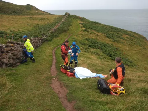Coastguards supporting Margaret Albery on the clifftop
