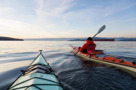 Stock image of a kayaker with kayak out at sea, the kayaker wearing a personal floatation device