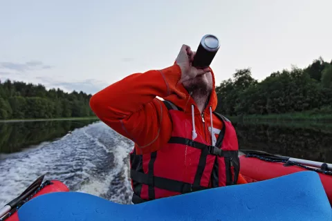 A man drinking from a can while at the helm of a motorboat