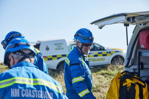 Coastguard Rescue Officers on a clifftop next to vehicles