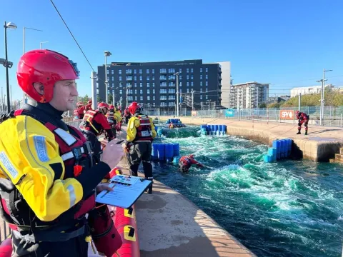 A coastguard wearing a dry suit watches a flood exercise