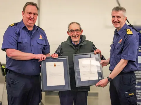 Paul 'Bud' White (centre) is presented with certificates by Divisional Commander Matt Pavitt (left) and Assistant Chief Coastguard Channel Operations John Craig (right)