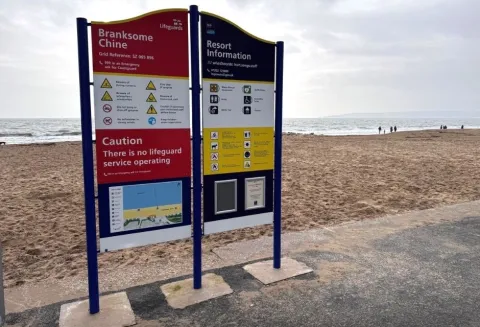 Image of a blue, yellow and white safety sign on a beach