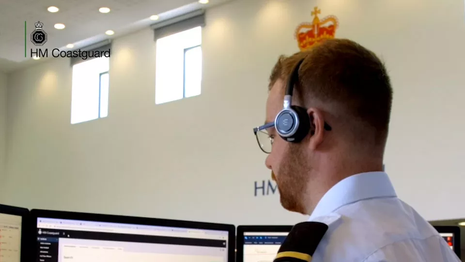 A Maritime Operations Officer wears a headset in a HM Coastguard operations centre
