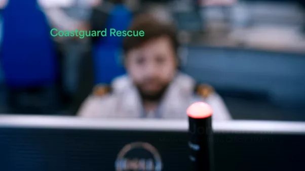 Blurred image of Coastguard in operations room with Coastguard Rescue on screen