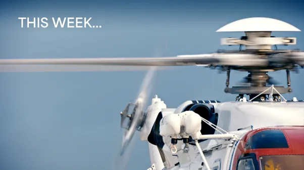 Edge of helicopter with moving blades and 'This Week...' message on screen