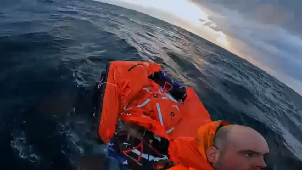 A man in a high visibility raft is floating in the middle of the ocean