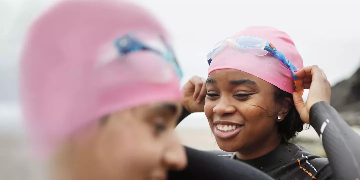 Swimmer putting on bright pink cap for visibility in the water