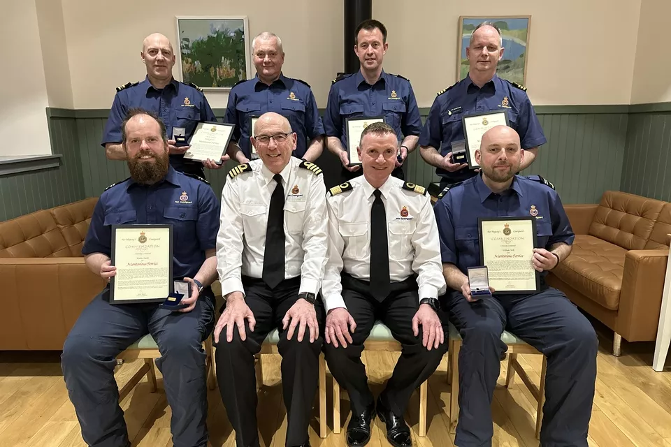 Coastguard team members holding their commendation awards
