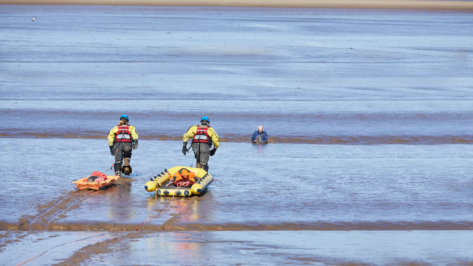 Two Coastguard Rescue Officers rescue a man stuck in mud