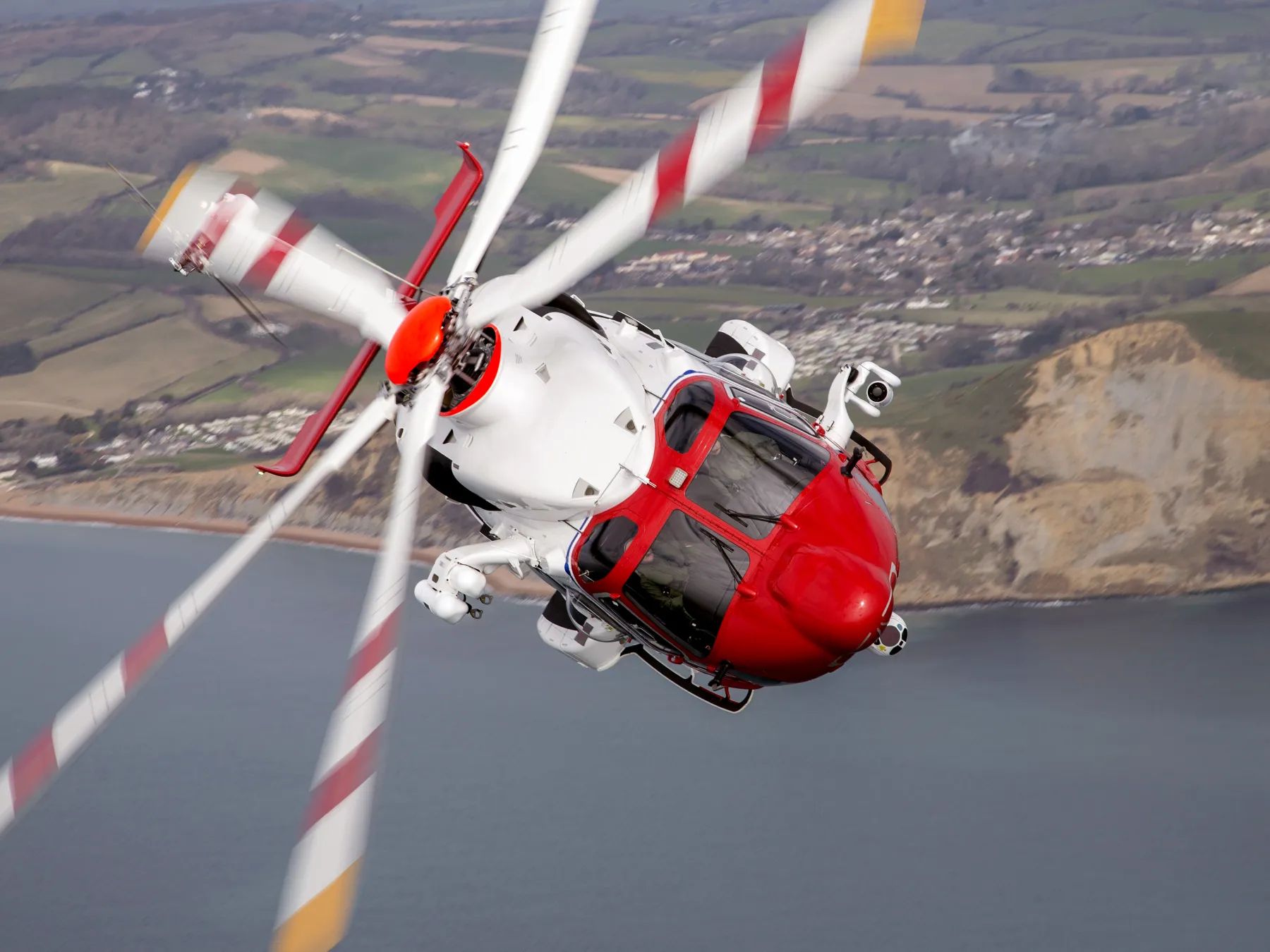 HM Coastguard helicopter banking right with coastline visible in background