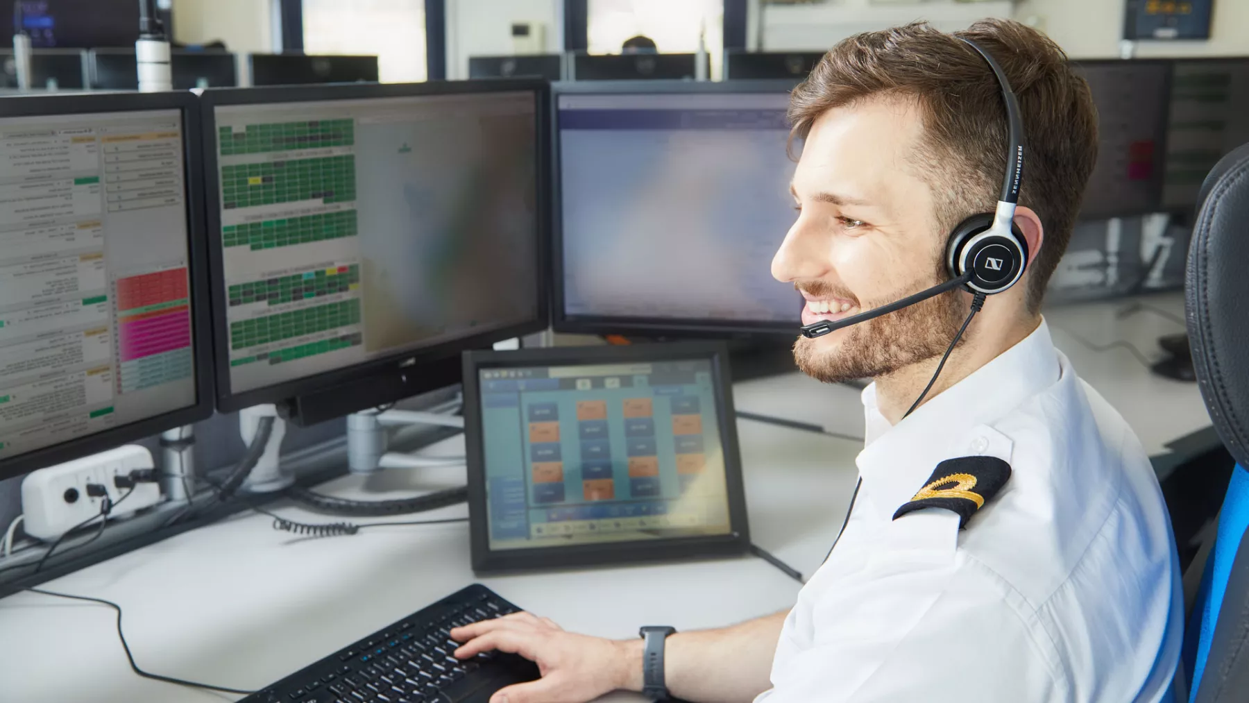 A young man wearing a headset in a HM Coastguard operations room