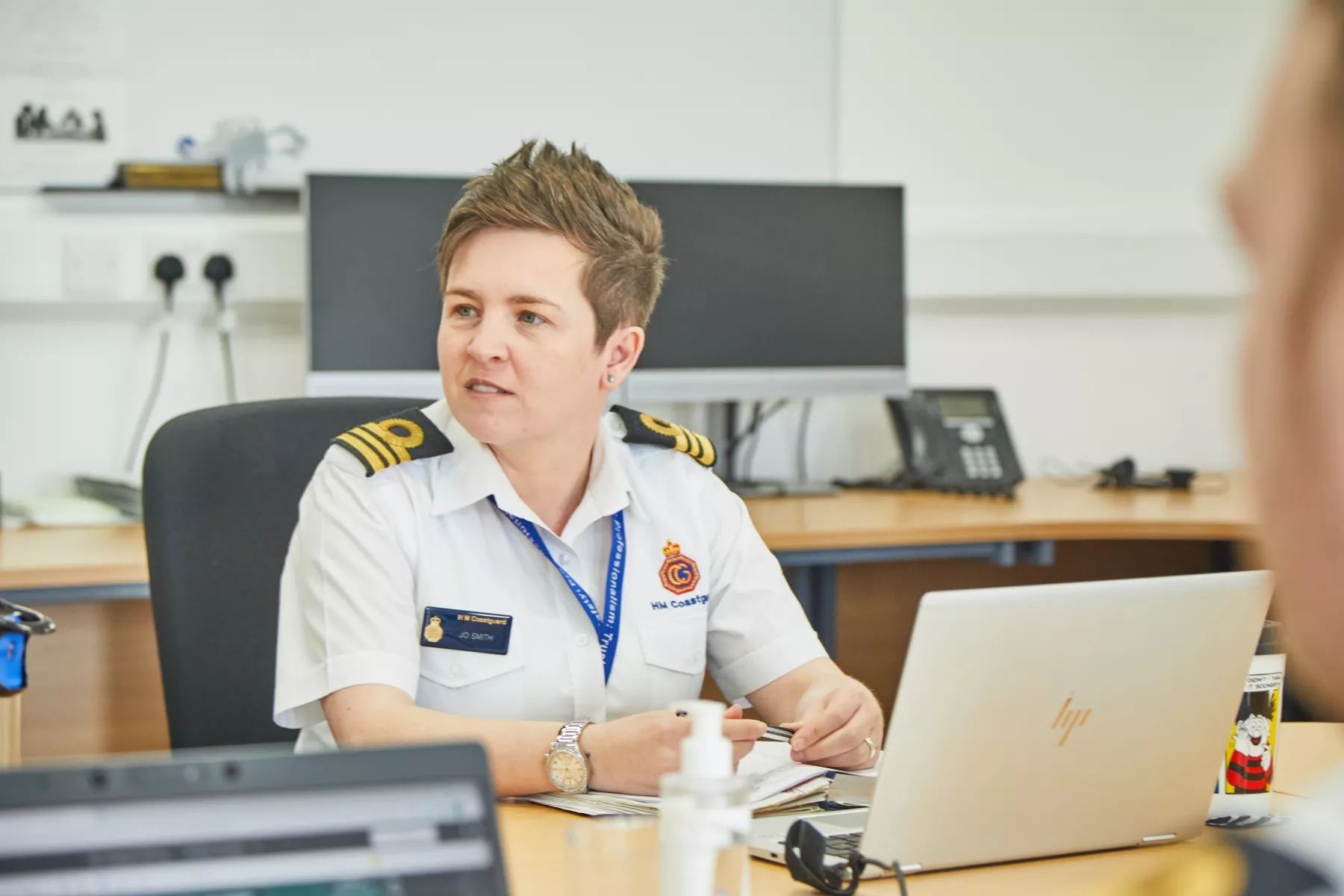 Jolene in white shirt HM Coastguard uniform in office looking off camera to right