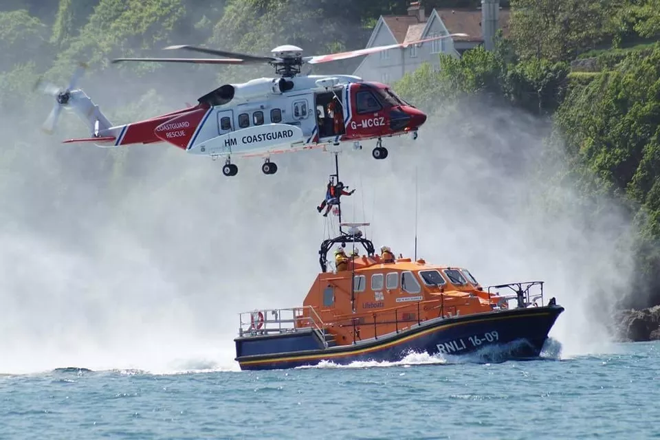 An HM Coastguard search and rescue helicopter hovers over an RNLI all-weather lifeboat