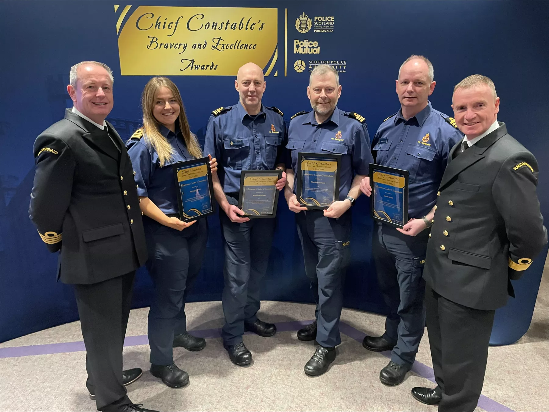 Members of HM Coastguard smiling and holding Bravery and Conduct awards from Police Scotland