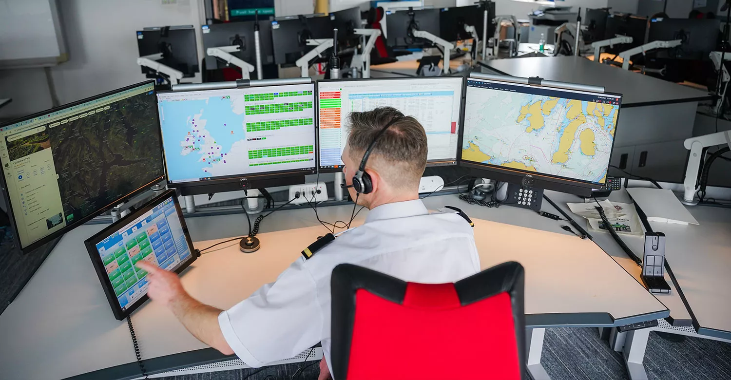 A maritime operations officer working at their desk with multiple screens