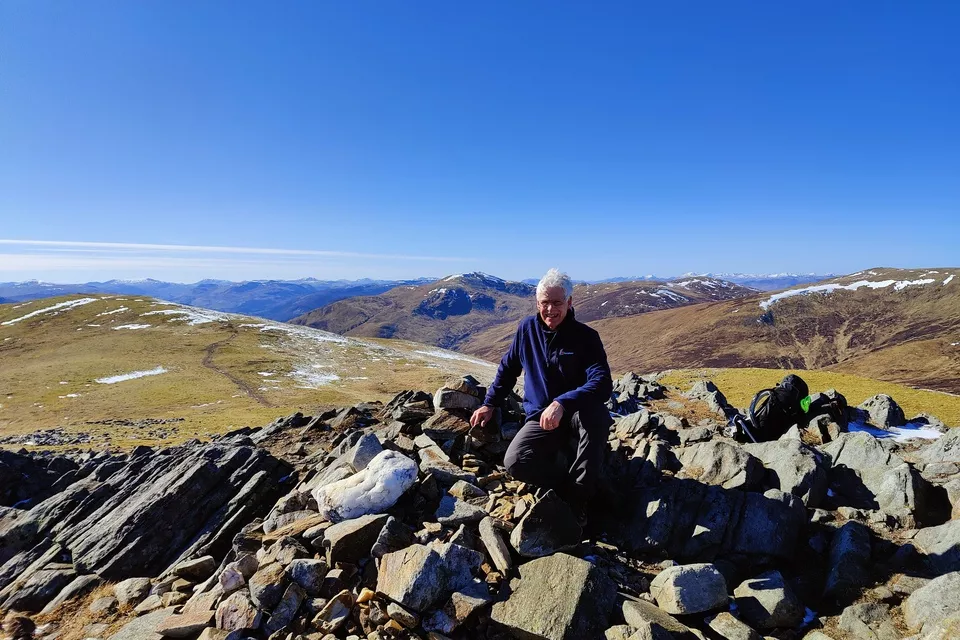 Man sits at the summit of Creag Mhor with a stunning view 