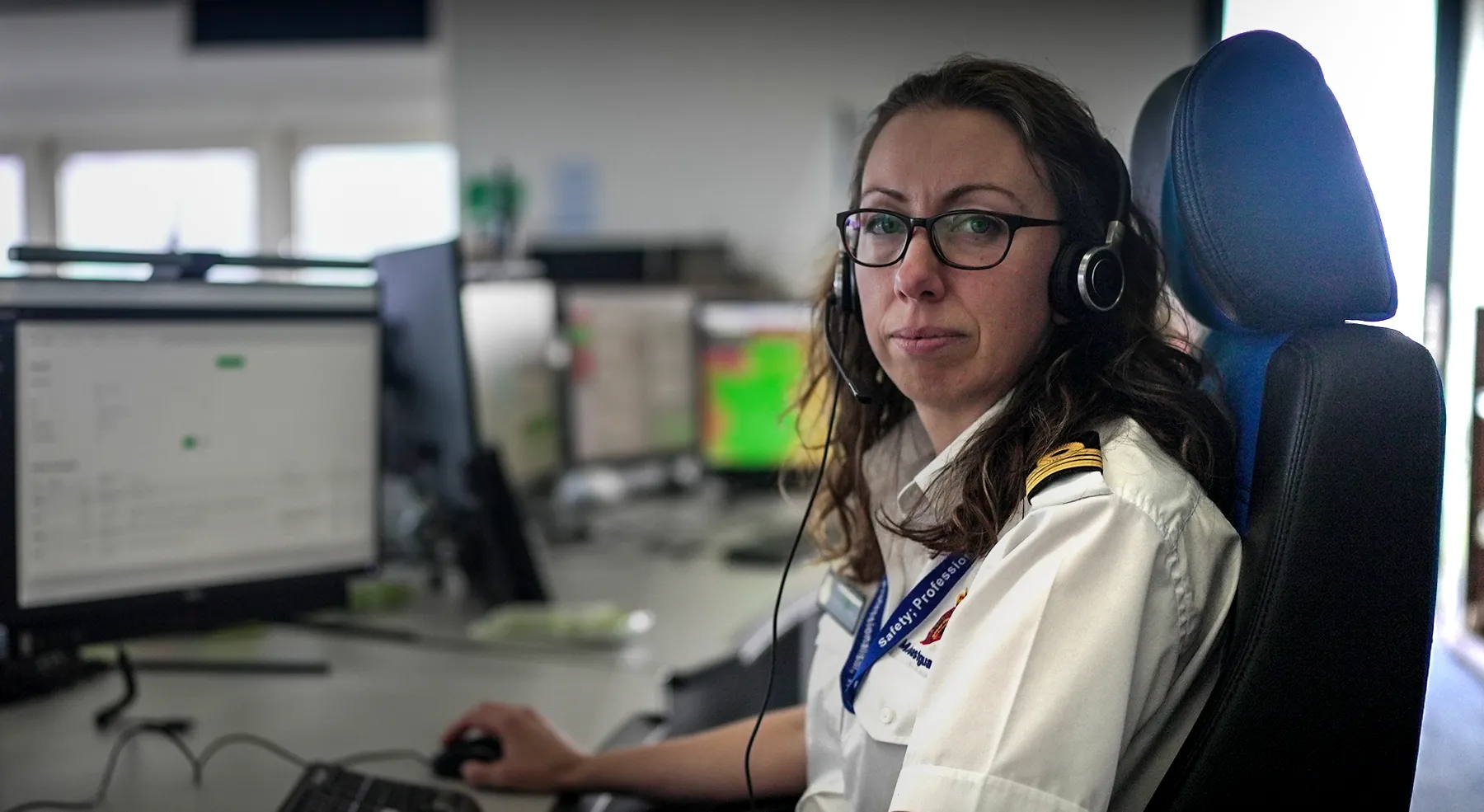 A female team leader in a maritime operations centre sits looking to the camera