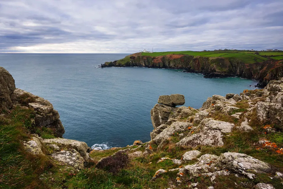 A coastal landscape with calm blue seas and rocky, steep cliffs