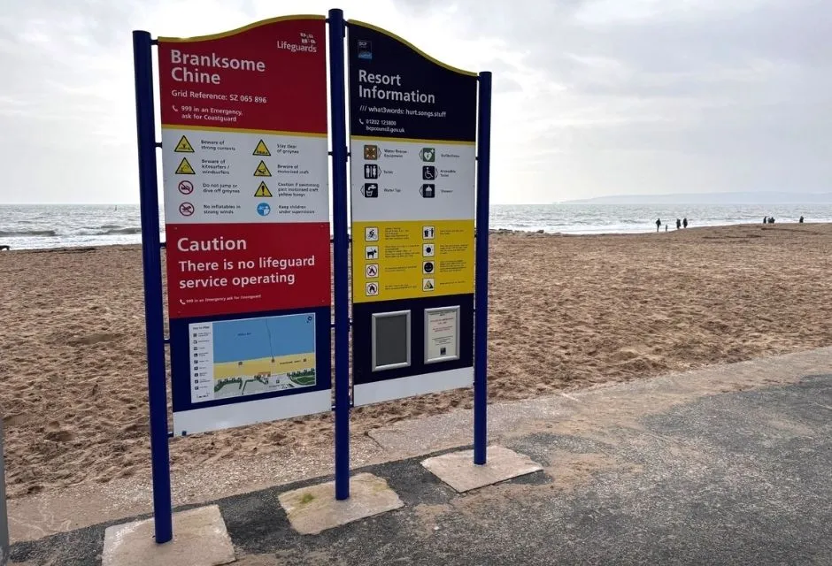 Image of a blue, yellow and white safety sign on a beach