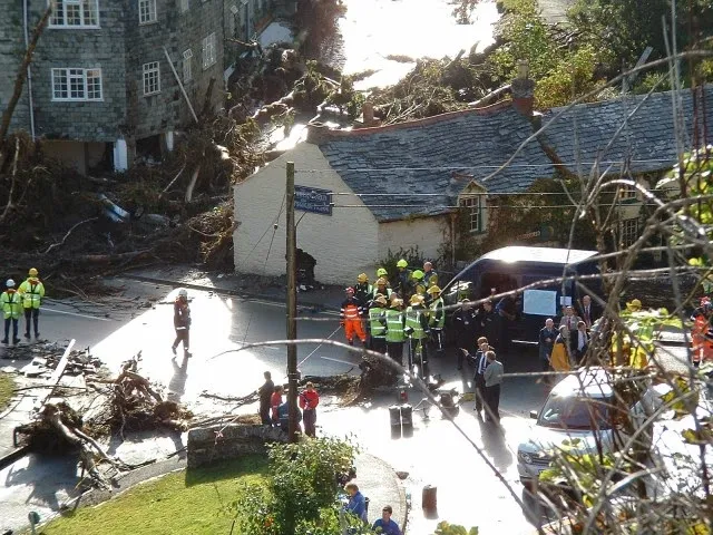 Emergency service personnel in Boscastle stand near damaged buildings
