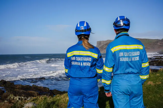 Members of HM Coastguard survey a clifftop view of the coast below