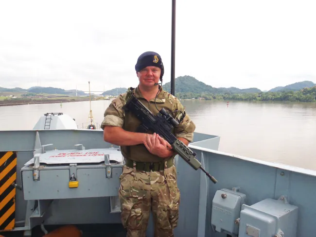 Jon Oliver on the deck of a vessel wearing Royal Navy uniform