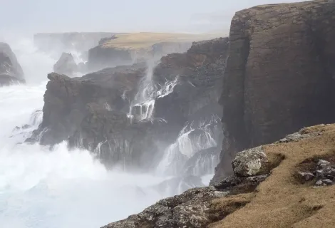 Waves crashing against cliffs.