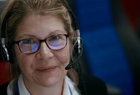 Maritime Operations Officer Rachel with headphones and glasses smiling at the camera from the documentary