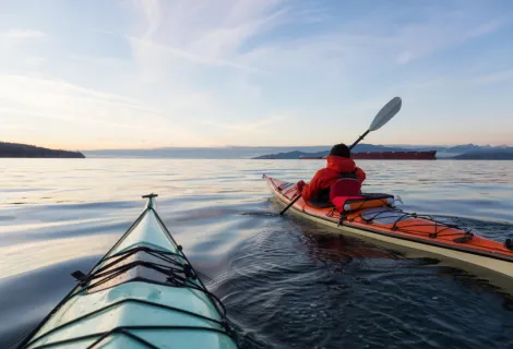 Stock image of a kayaker with kayak out at sea, the kayaker wearing a personal floatation device
