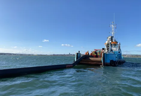 A counter-pollution boom is delivered from the back of a vessel in the sea off Aberdeen