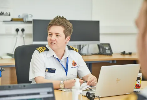 Jolene in white shirt HM Coastguard uniform in office looking off camera to right