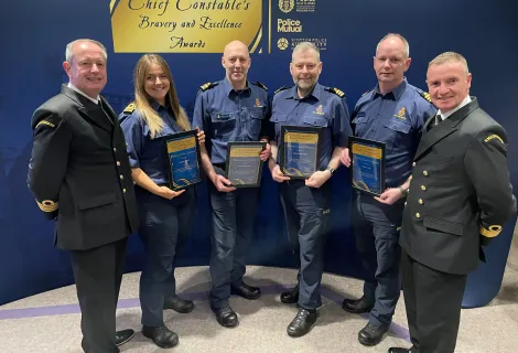 Members of HM Coastguard smiling and holding Bravery and Conduct awards from Police Scotland