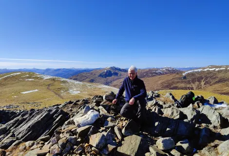 Man sits at the summit of Creag Mhor with a stunning view 