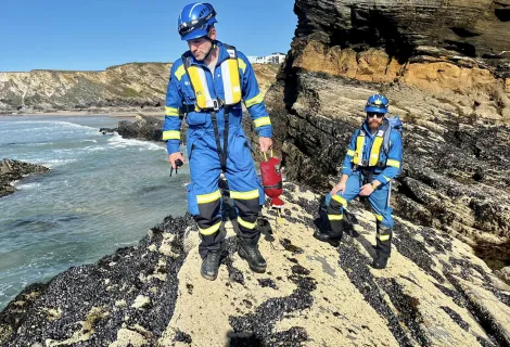 Coastguard Rescue Officers from Newquay Coastguard Rescue Team patrol rocks on the shore 