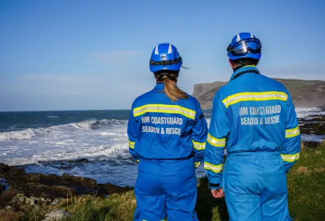 Members of HM Coastguard survey a clifftop view of the coast below