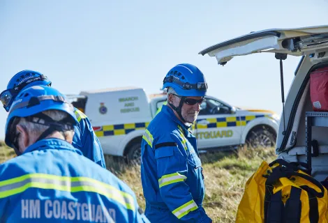 Coastguard Rescue Officers on a clifftop next to vehicles