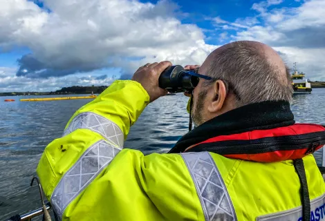 A Counter Pollution and Salvage officer watches out to sea through binoculars