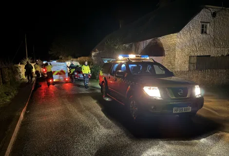An HM Coastguard vehicle with blue light on, parked in a road at night